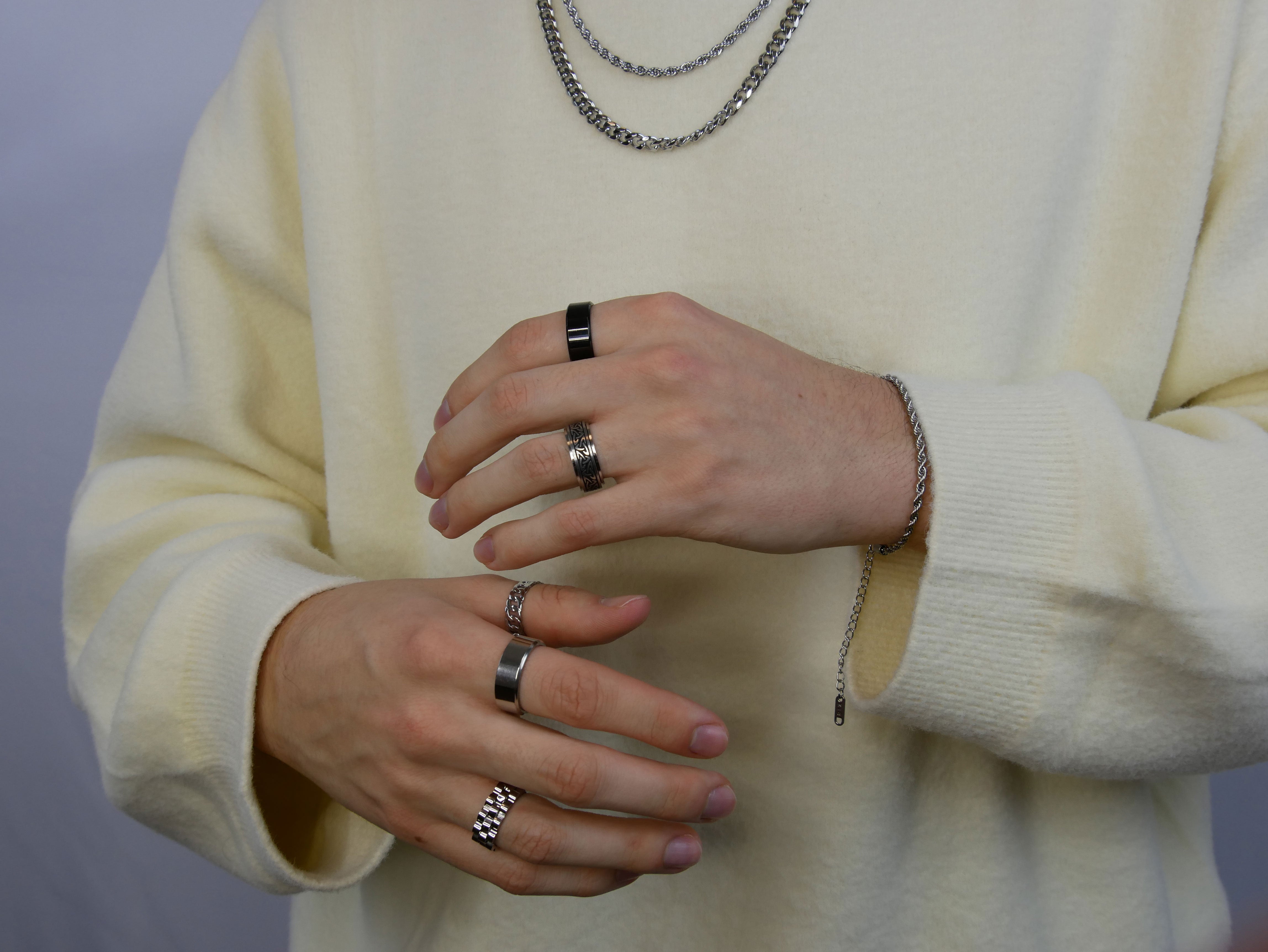 sieraden voor mannen, handen met ringen en kettingen die over trui heen hangen